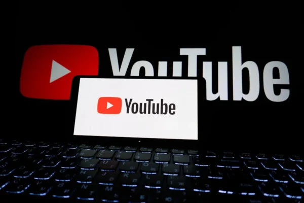 Close-up of YouTube logo displayed on a laptop screen in a dark environment.