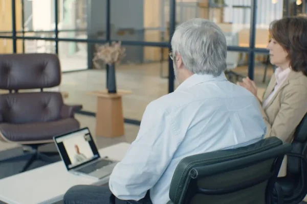 Elderly professionals engaging in an online meeting in a modern office setting.