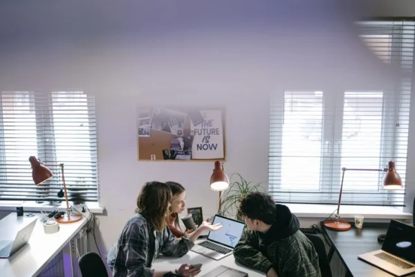A group of people discussing ideas around laptops in a bright, modern office space.