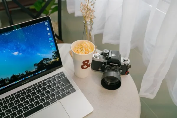 Cozy indoor workspace featuring a laptop, vintage camera, and coffee cup.